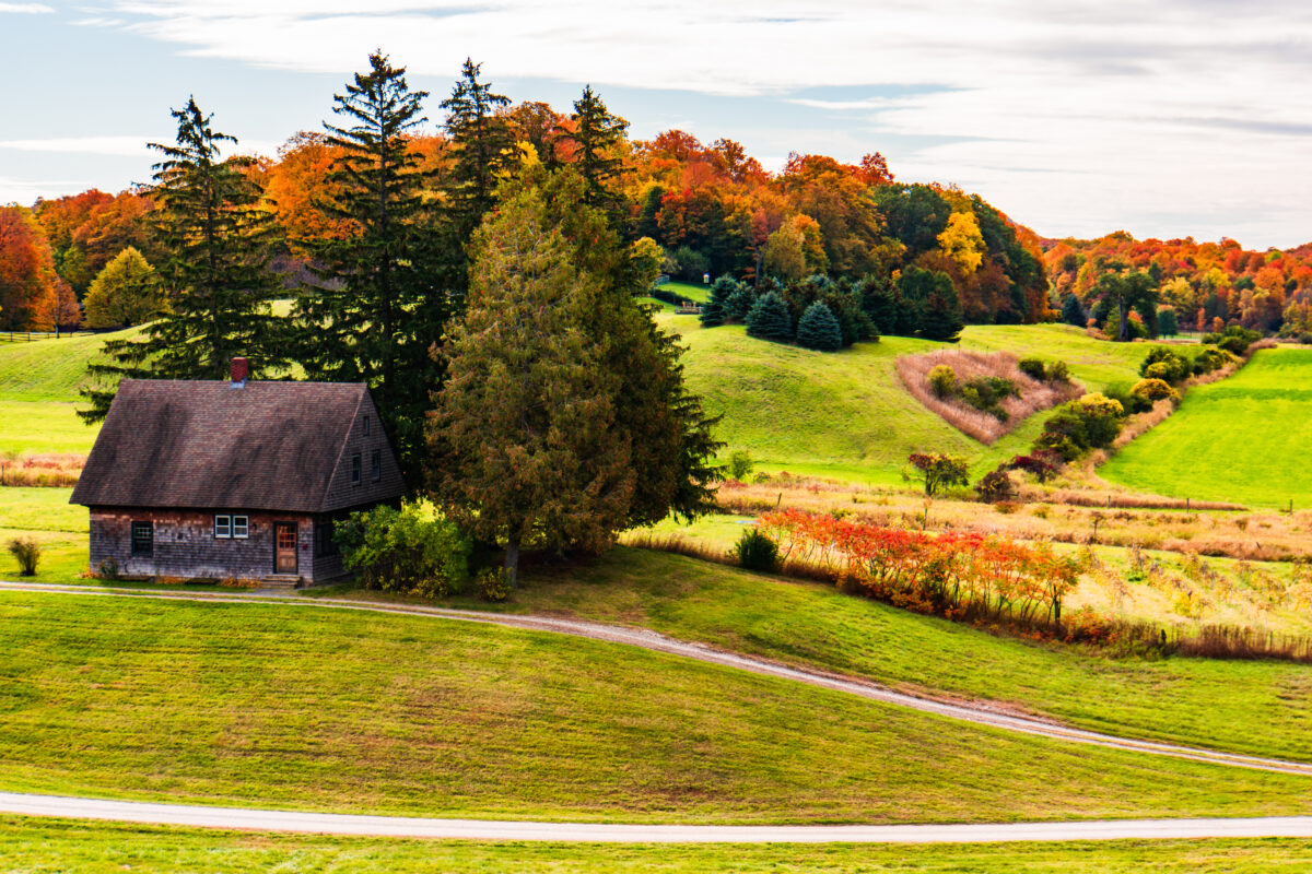 rolling hills of Shelburne Farms with small farm building in autumn