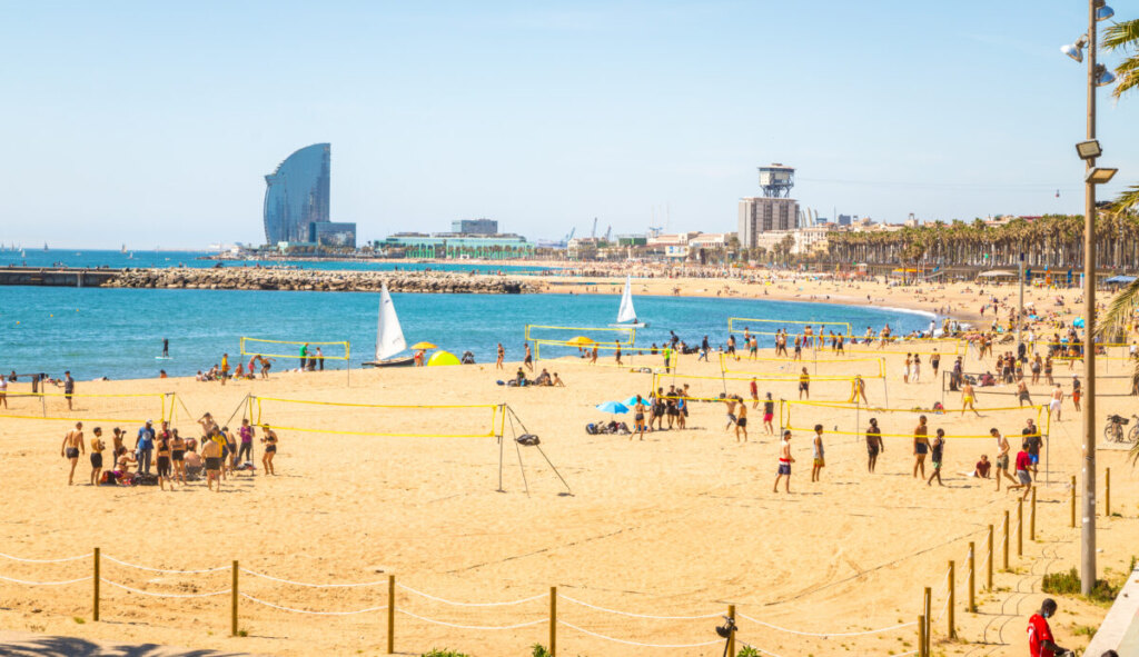 People playing beach sports and enjoying the beach of Barceloneta Beach in Barcelona, Spain