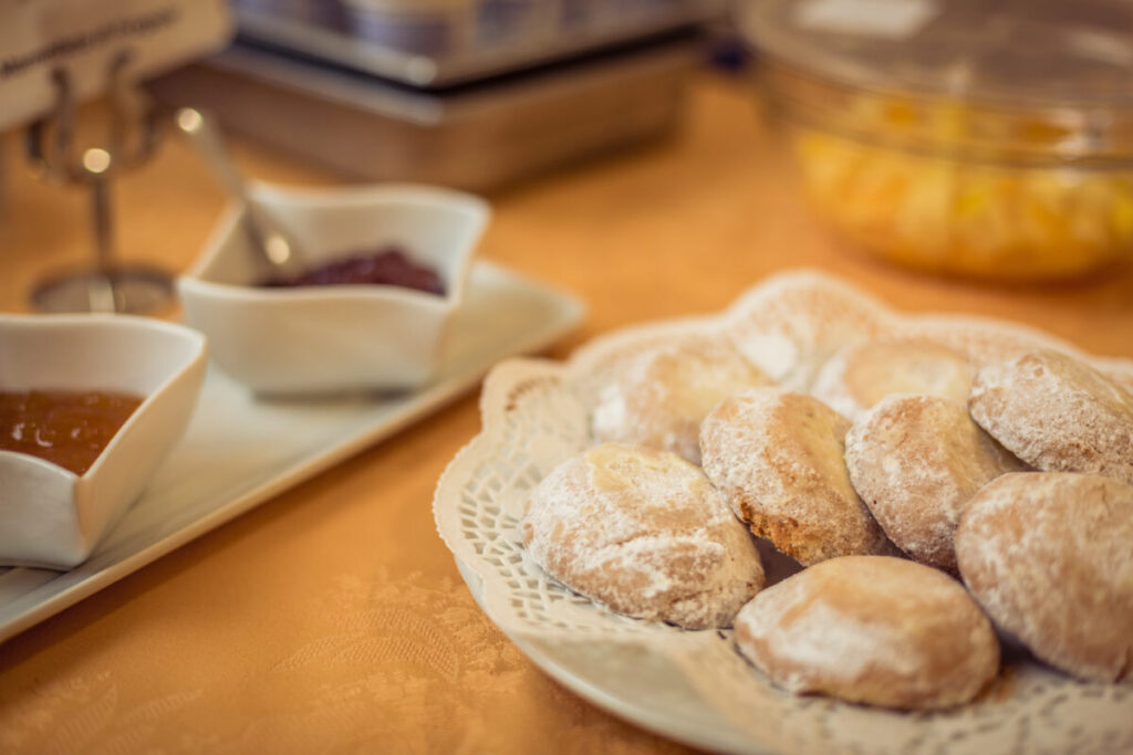 Close-up of traditional Sicilian cassatelle sweets and two bowls of jam on a breakfast table