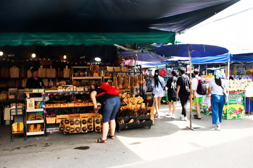 Locals and tourists walking around the stalls, products, and goods at the Chatuchak Weekend Market in Bangkok, Thailand