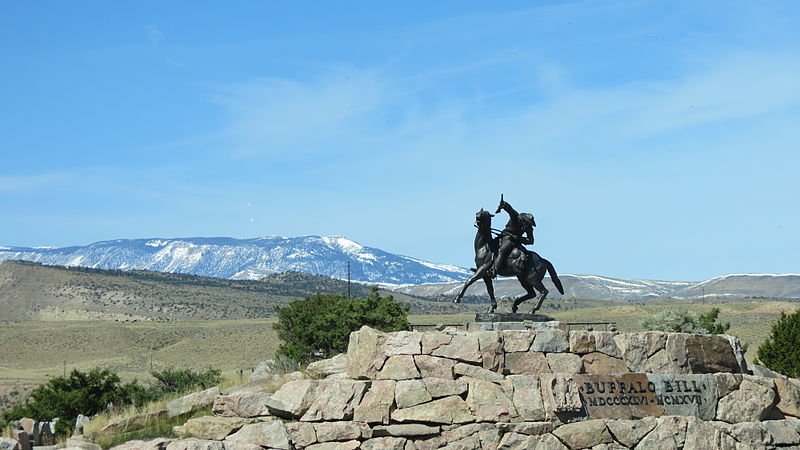 Cody, Wyoming, the gateway to Yellowstone, featuring the historic Cody Main Street with rustic storefronts and a view of the Shoshone River winding through the town.