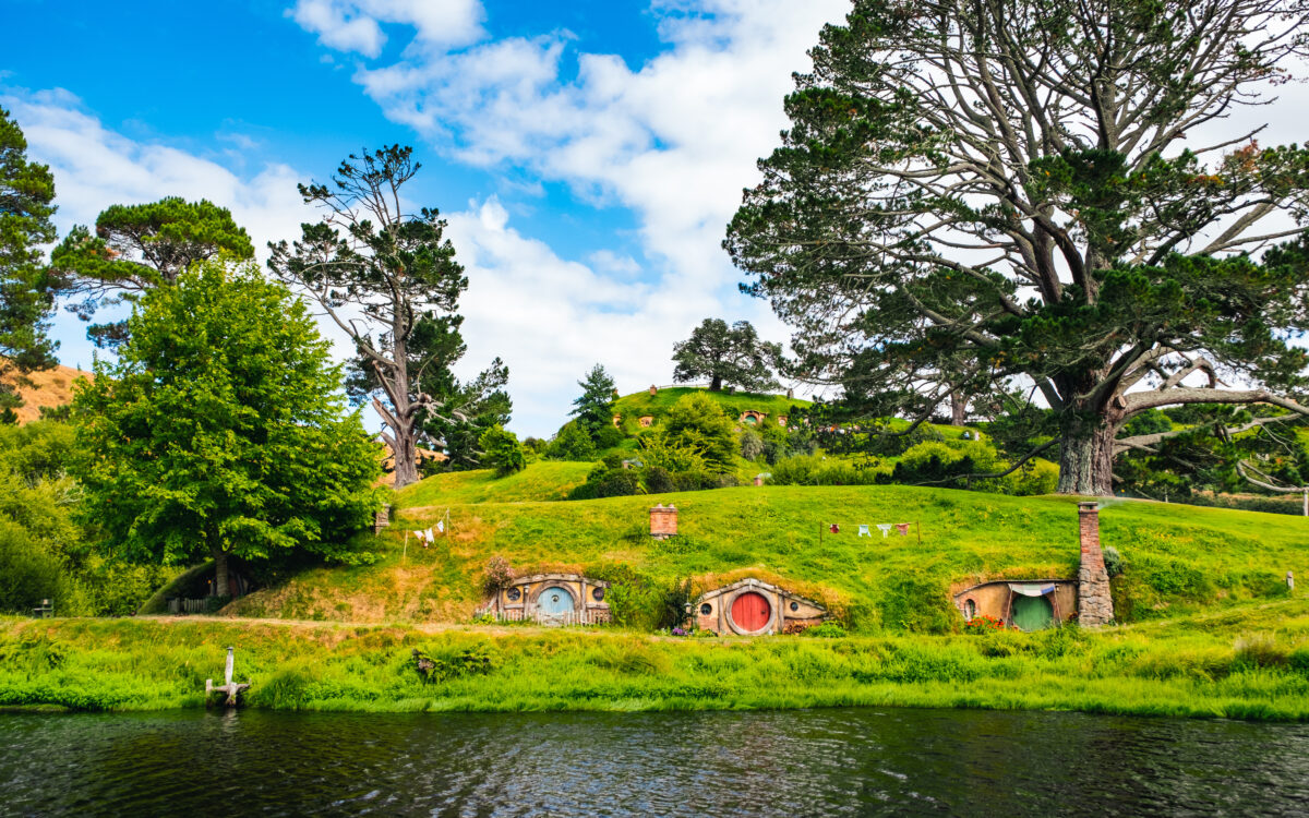 Charming hobbit holes with round doors nestled in green hills at Hobbiton movie set Matamata New Zealand