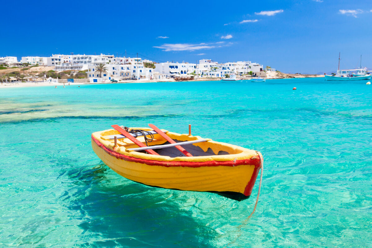 Fishing port of Koufonisi island in Greece's Cyclades archipelago, showcasing traditional white buildings, crystal-clear turquoise waters, and small fishing boats - a perfect example of underrated Mediterranean beauty.