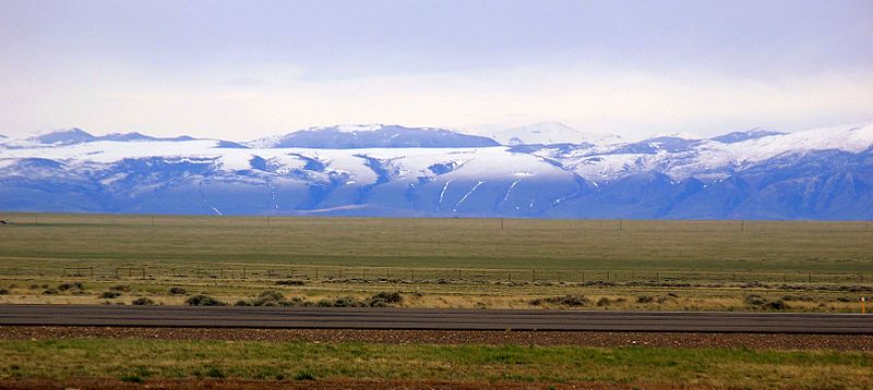 A serene snapshot of Powell, Wyoming, featuring the iconic Heart Mountain in the distance and a blend of rural landscapes, showcasing the town's tranquil charm.