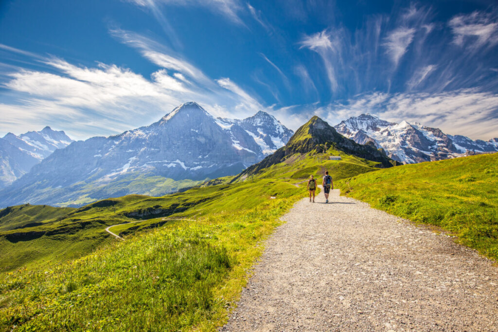 Couple hiking a trail to Kleine Scheidegg with the view of the Swiss Alps