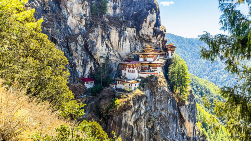 Panoramic view of the Tiger's Nest Monastery in Bhutan, nestled in the mountains and surrounded by lush greenery