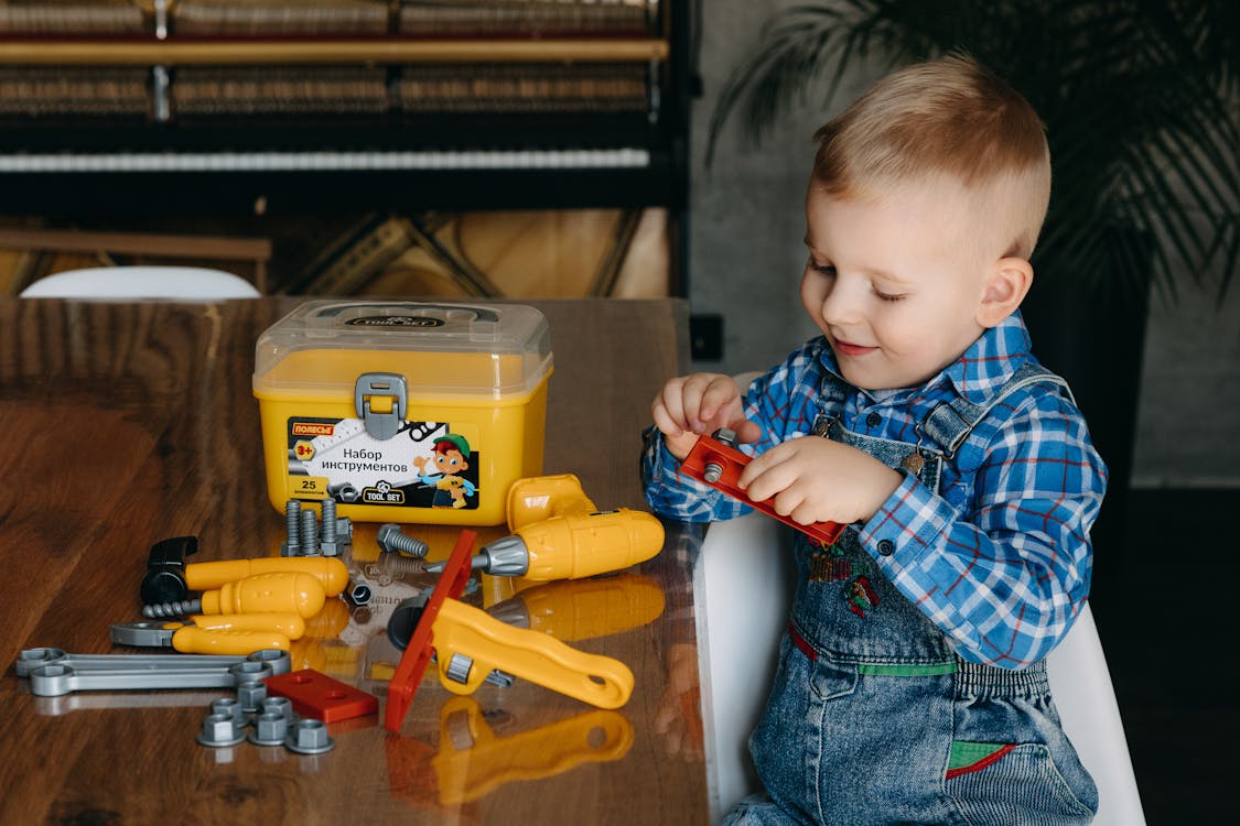 A young boy playing with a toy tool set
