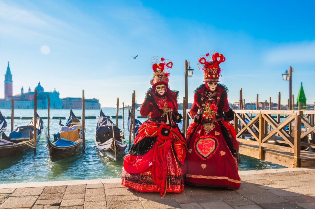 Two people in costumes and wearing masks for Venice Festival in Grand Canal, Venice, Italy