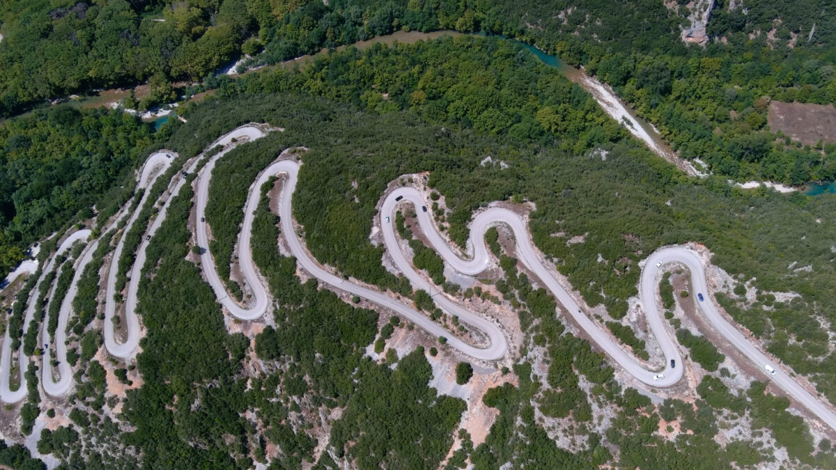 Mountain road winding along Voidomatis River with views of Vikos Gorge in the Zagori region of Northern Greece